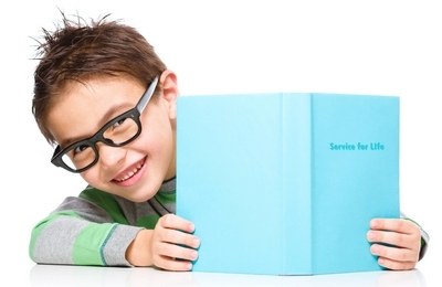 Cute little child plays with book and wearing glasses while sitting at table, isolated over white